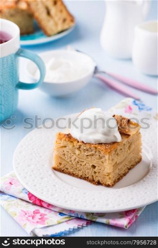 Homemade apple cake, slice with cream on plate, served for tea, selective focus