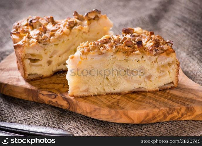 Homemade apple pie with cinnamon and nuts on olive wood board, rustic style, selective focus
