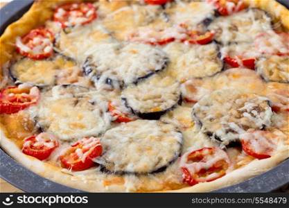 Homemade aubergine, tomato and cheese pizza still in the pan and fresh from the oven