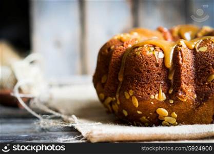 Homemade autumn cake with pumpkin seeds and caramel on wooden background