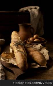 Homemade baguette french bread with parchment paper on wood table. Bread at wooden tabletop as baking concept