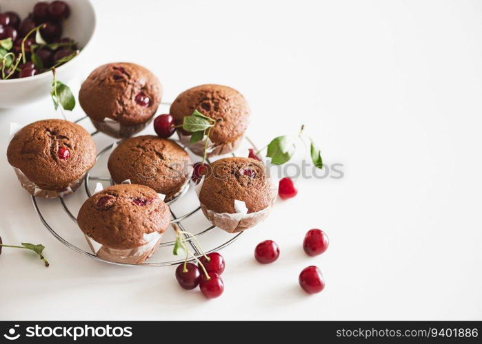 Homemade baked cherry muffins with fresh berries on white wooden table