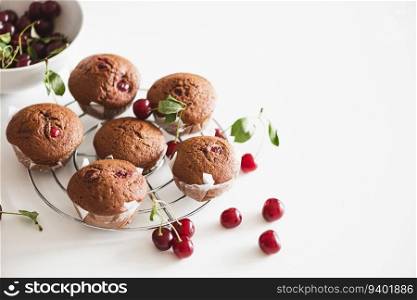Homemade baked cherry muffins with fresh berries on white wooden table