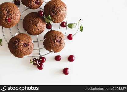 Homemade baked cherry muffins with fresh berries on white wooden table. Top view