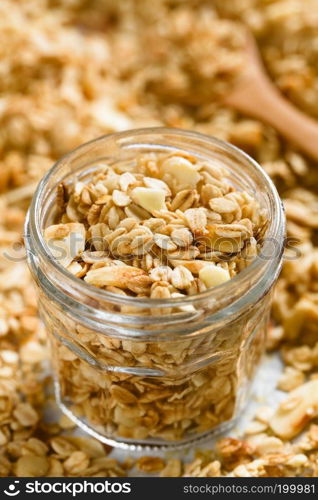 Homemade baked crunchy oatmeal, sliced almond, honey and coconut oil breakfast granola in glass jar  Selective Focus, Focus in the middle of the image . Oatmeal, Almond and Honey Granola