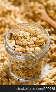 Homemade baked crunchy oatmeal, sliced almond, honey and coconut oil breakfast granola in glass jar  Selective Focus, Focus in the middle of the image . Oatmeal, Almond and Honey Granola