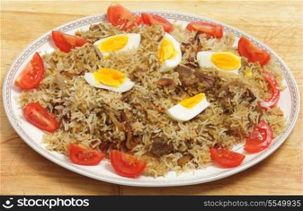 Homemade beef biryani garnished with egg, tomato and cucumber, on a serving dish