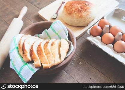 Homemade Bread Ready To Eat With Loaf Of Bread, eggs and bakery tools on wood background