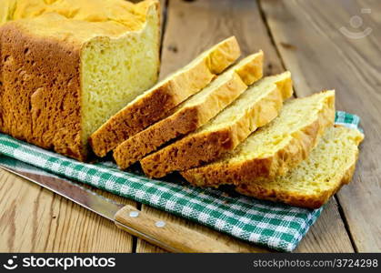 Homemade bread yellow on a green napkin, knife on the background of wooden boards