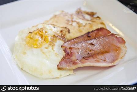 Homemade breakfast of bacon and eggs in white square plate