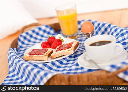 Homemade breakfast on wicker tray with checked teacloth in bedroom