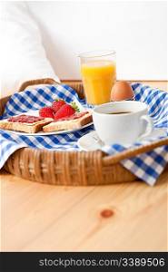 Homemade breakfast on wicker tray with checked teacloth in bedroom