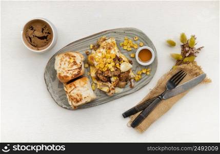 Homemade breakfast with Breads and Stuffed omelette with chicken, garlic and cheese sprinkled with sweet corn and honey on Ceramic plate served with cup of coffee. Top view, Copy space, Selective Focus.