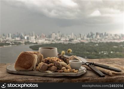 Homemade breakfast with Breads and Stuffed omelette with chicken, garlic and cheese sprinkled with sweet corn and honey served with cup of coffee on rustic old wooden table with beautiful scenery in the morning. Selective Focus.