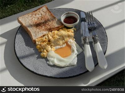 Homemade breakfast with Corn cheese omelette, Fried egg and Toast Served with Tomato ketchup on Ceramic plate. Selective Focus.