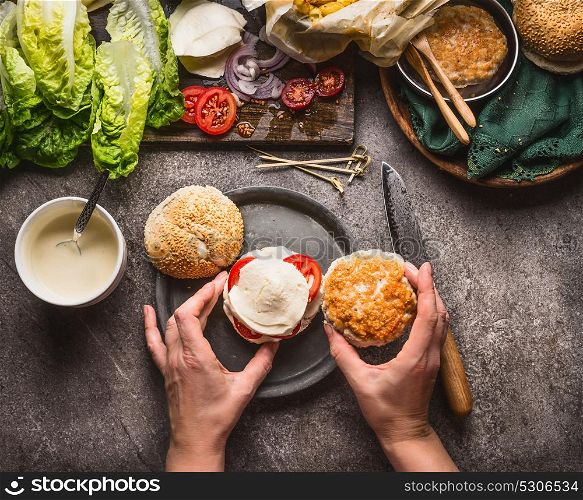Homemade burger . Female woman hands making burger on kitchen table background with ingredients, top view