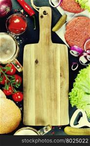 Homemade burger ingredients, beer and empty cutting board - food background concept