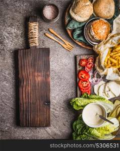 Homemade burger ingredients on kitchen table background with cutting board, top view, place for text