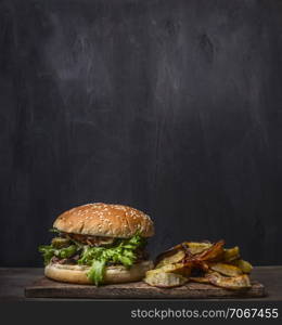 homemade burger with tuna and fried potatoes with dill and garlic on a cutting board on wooden rustic background border, place for text