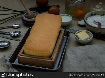 Homemade butter cake or pound cake with ingredients (eggs, flour, milk, butter with honey) and rolling pin, whisk eggs. Selective focus.