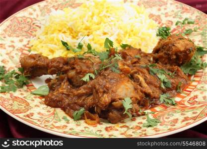 Homemade butter chicken masala with yellow and white rice, garnished with chopped coriander leaves.