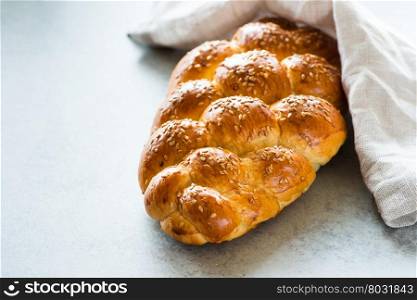 Homemade challah bread with sesame seeds over grey background, selective focus