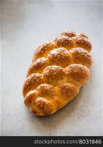 Homemade challah bread with sesame seeds over grey background, selective focus
