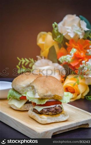 homemade cheese burgers . Delicious homemade gourmet cheese burgers made from beef with fresh ingredients placed on wooden platters
