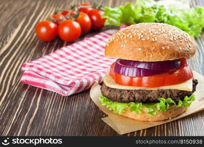 Homemade cheeseburger with beef patties and fresh salad on seasame buns, sered on brown wooden table.. Homemade cheeseburger on brown wooden surface.