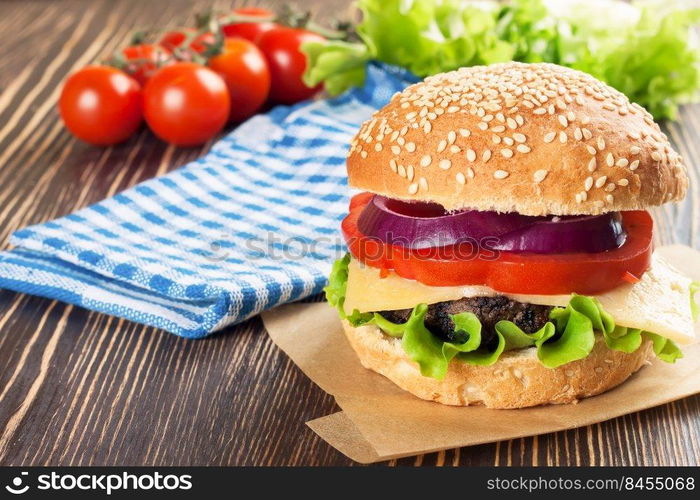 Homemade cheeseburger with beef patties and fresh salad on seasame buns, sered on brown wooden table.. Homemade cheeseburger on brown wooden surface.