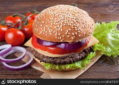 Homemade cheeseburger with beef patties, fresh salad, tomatoes and onion on seasame buns, served on brown wooden table.. Homemade cheeseburger on brown wooden surface.