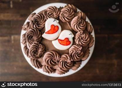 Homemade chocolate cake, culinary masterpiece decorated with cookies in glaze, top view. Sweet dessert on wooden background