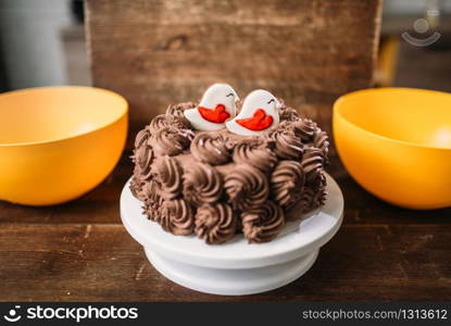 Homemade chocolate cake decorated with cookies in glaze. Sweet dessert on wooden background