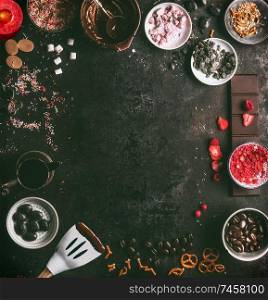 Homemade chocolate factory background. Preparation of chocolate with various topping: candy, marshmallow, nuts, liquorice, caramel, dried fruits, and spices. Melted chocolate in bowls with spatula