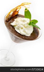 Homemade chocolate mousse in a martini glass with cream, a sprig of mint and a caramelised sugar decoration