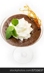 Homemade chocolate mousse in a martini glass with cream, a sprig of mint and a caramelised sugar decoration