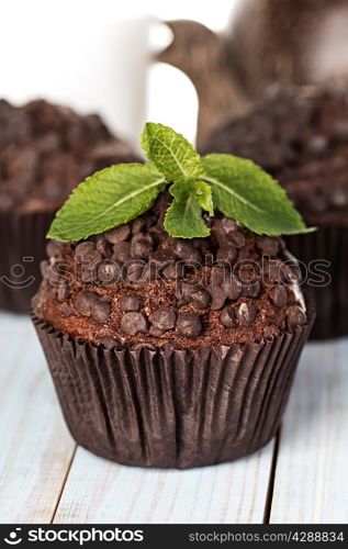 Homemade chocolate muffins in paper cupcake holder on a wooden background