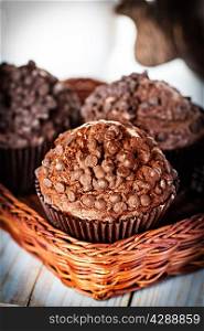 Homemade chocolate muffins in paper cupcake holder on a wooden background