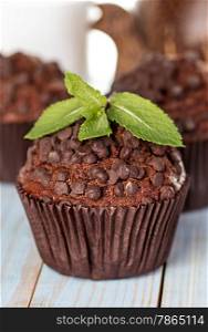 Homemade chocolate muffins in paper cupcake holder on a wooden background
