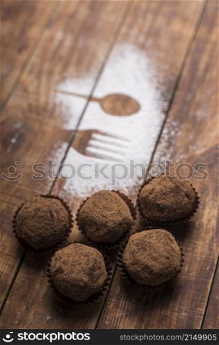 homemade chocolate truffle candies with cocoa powder near spoon fork shape sugar powder