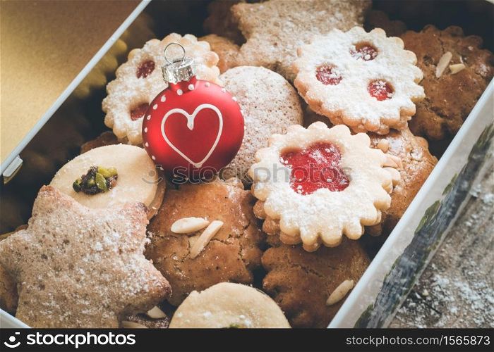 Homemade Christmas cookies and a Christmas bauble in a box, lying on a rustic wooden table