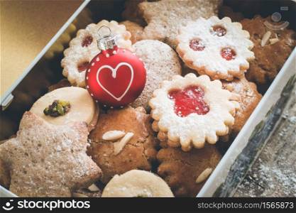 Homemade Christmas cookies and a Christmas bauble in a box, lying on a rustic wooden table
