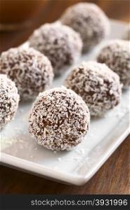 Homemade coconut rum balls on plate, photographed with natural light (Selective Focus, Focus on the first ball)