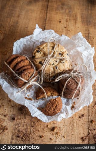 Homemade corded wholegrain cookies with oatmeal, linen and sesame seeds and traditional american cookies with chocolate chips on dark rustic wooden table . Healthy vegan food concept.. Various shortbread, oat cookies, chocolate chip biscuit.