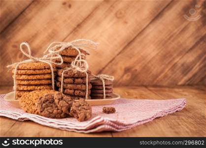 Homemade corded wholegrain cookies with oatmeal, linen and sesame seeds and traditional cookies with chocolate chips on dark rustic wooden table.. Various shortbread, oat cookies, chocolate chip biscuit on dark rustic wooden table.