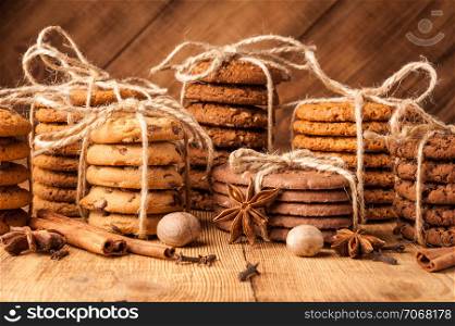 Homemade corded wholegrain cookies with oatmeal, linen and sesame seeds and traditional cookies with chocolate chips on dark rustic wooden table and spice.. Various shortbread, oat cookies, chocolate chip biscuit and spice on dark rustic wooden table.