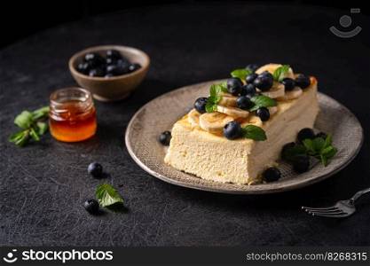 Homemade cottage cheese bake cake casserole with berries and banana on black background. Cottage cheese casserole