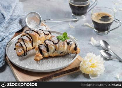 Homemade croissant served with black coffee or americano. Delicious breakfast with fresh croissant and coffee. Croissant and black coffee and chamomile with copy space in top view or flat lay style. Croissant and coffee for coffee break.