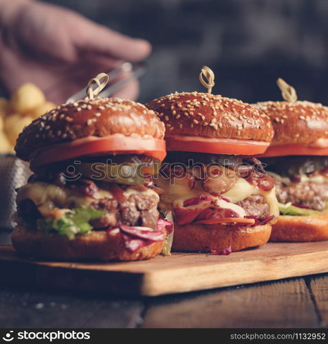 Homemade delicious juicy burger with beef, cheese, tomato and caramelized onion and potato balls. Toned image.