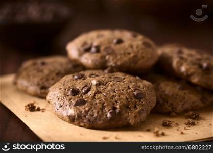 Homemade double chocolate chip cookies, photographed on dark wood with natural light (Selective Focus, Focus one third into the first cookie)